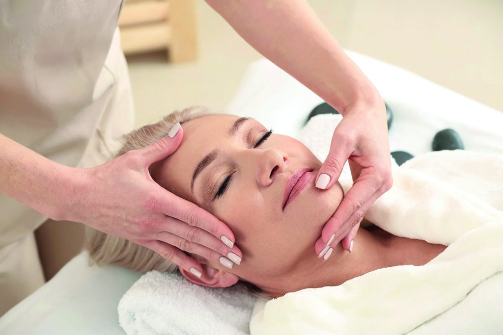 Mature woman receiving face massage in beauty salon